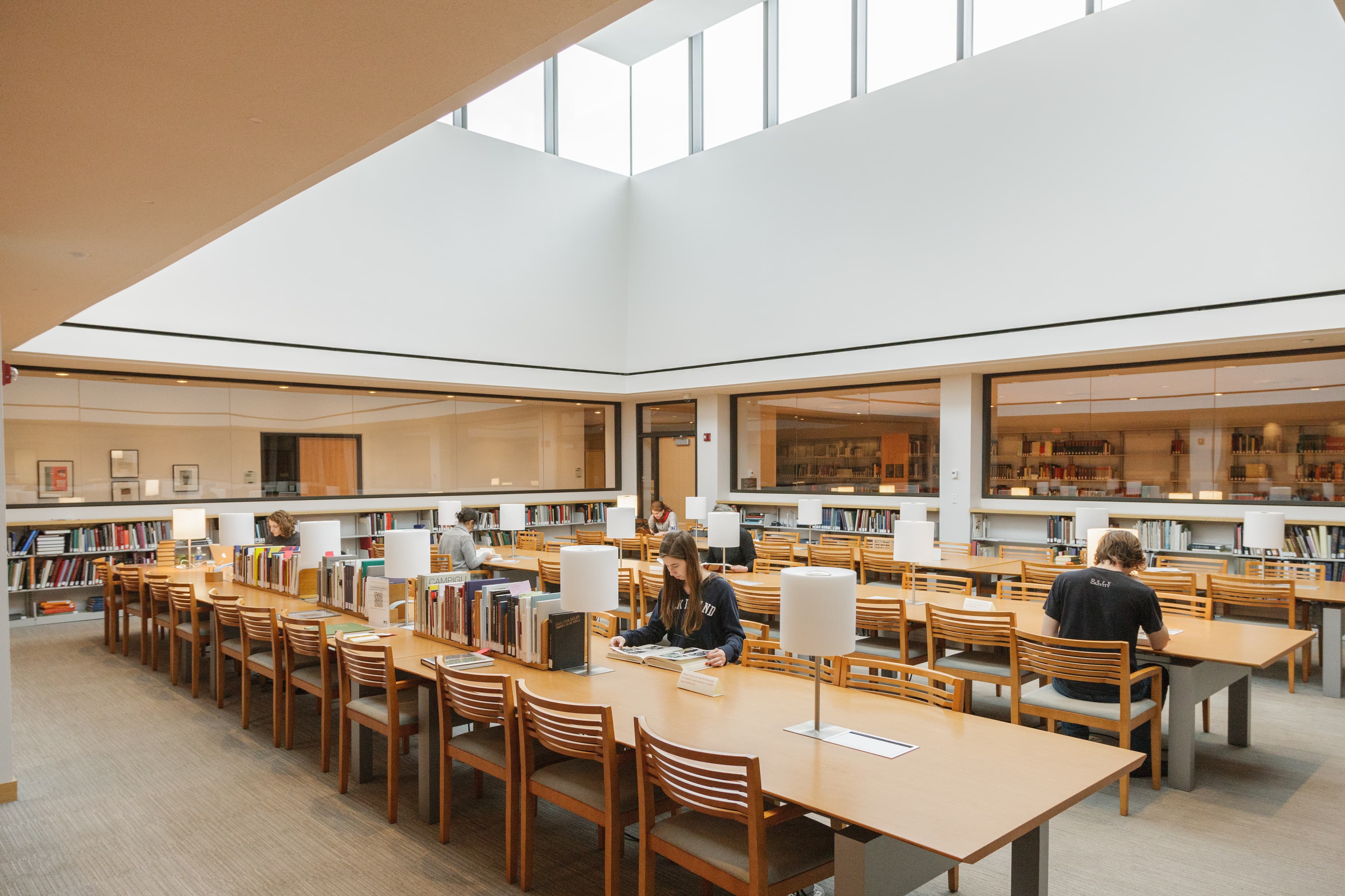 People sitting and reading at tables in a library.