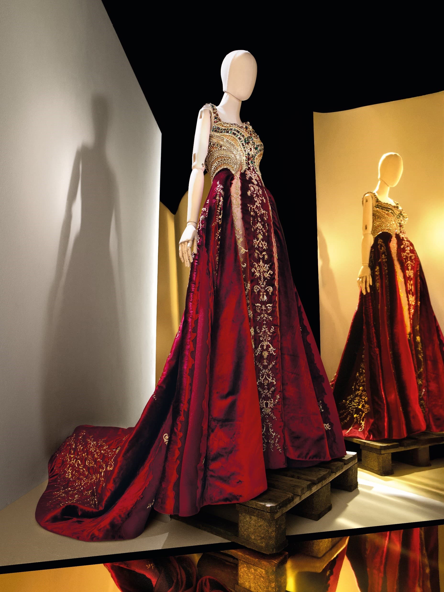 Red velvet gown on white mannequin with gold background from a low perspective looking up