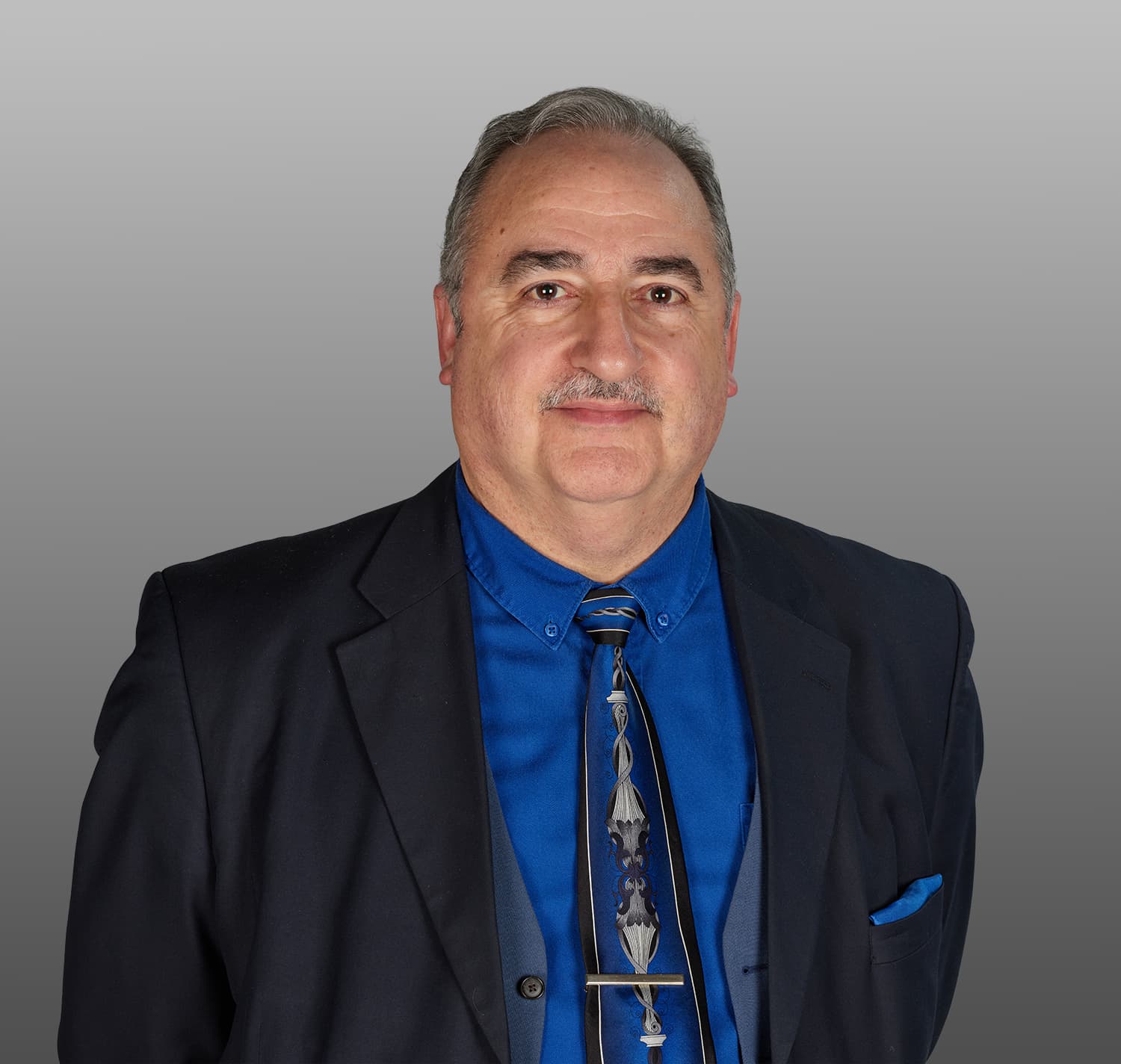 Photo of a man with a black blazer and blue shirt