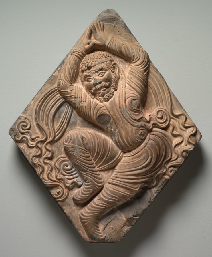 A tan architectural tile showing a dancing figure.