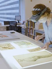A conservator works with drawings on paper.