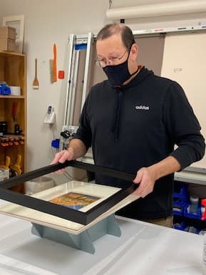 A technician frames an artwork.