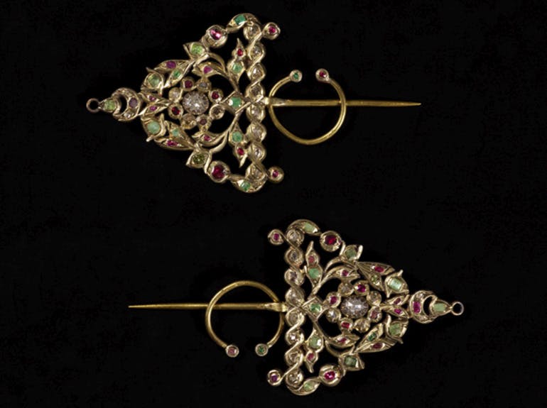 Two triangle-shaped gold bejeweled earrings, one above the other pointing in opposite directions