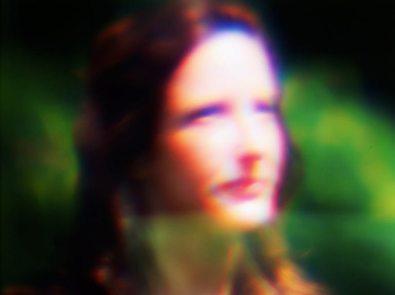A blurred color photo of a woman's face in half profile