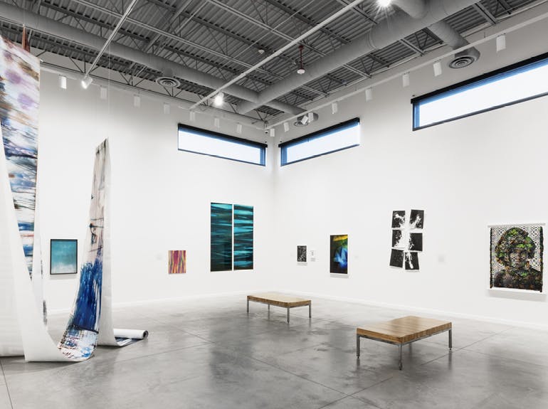 A photo of a white-walled art gallery with contemporary artworks on view