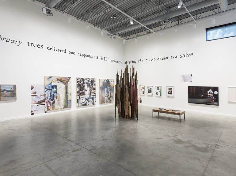 A photo of a white-walled art gallery with contemporary artworks on walls and floor