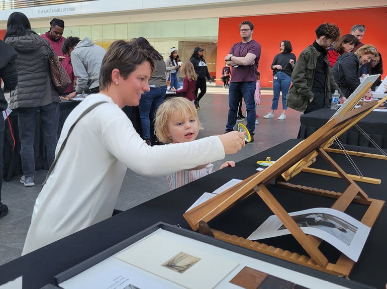 child and mom looking at art with magnifying glass