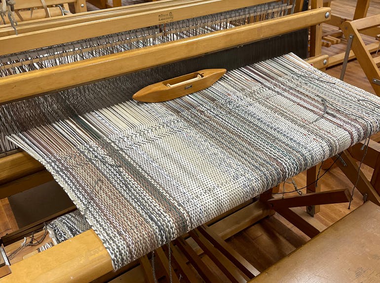 banner image of a loom with woven fabric