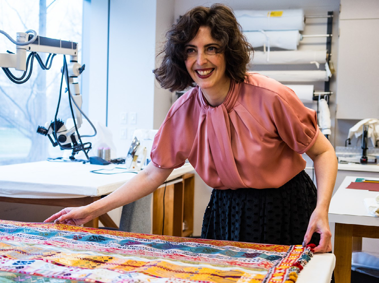 A conservator carefully handles an intricate textile